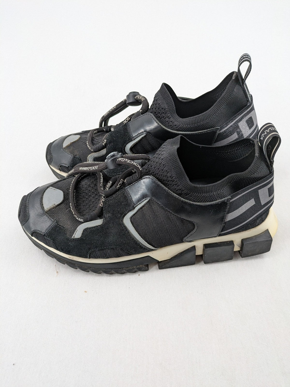Dolce & Gabbana black sneakers with logo laces and segmented sole design.