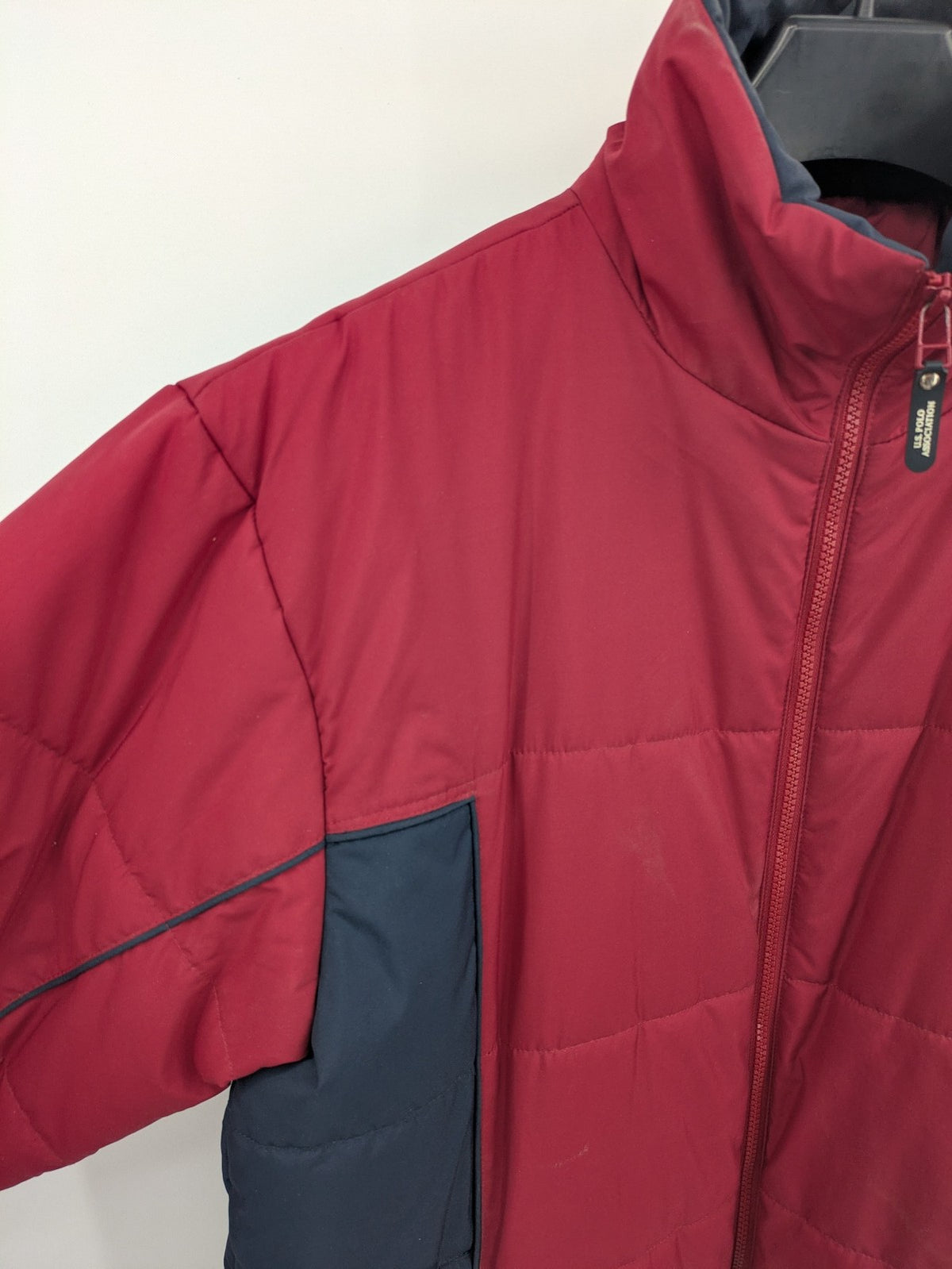 US Polo Assn. puffer jacket navy red two-tone design with embroidered logo and zip pockets.