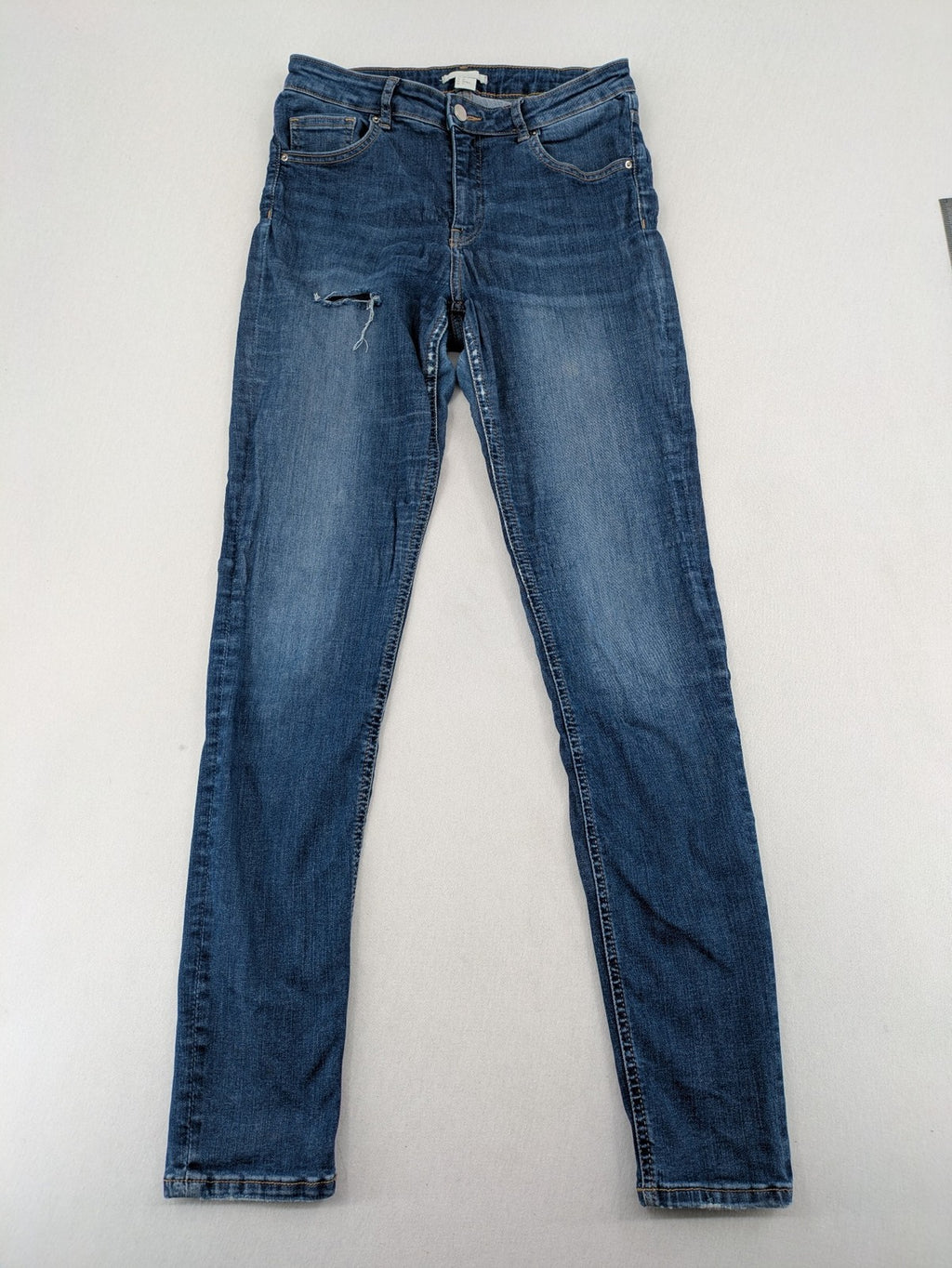 H&M blue skinny jeans with distressed details and comfortable stretch denim material.