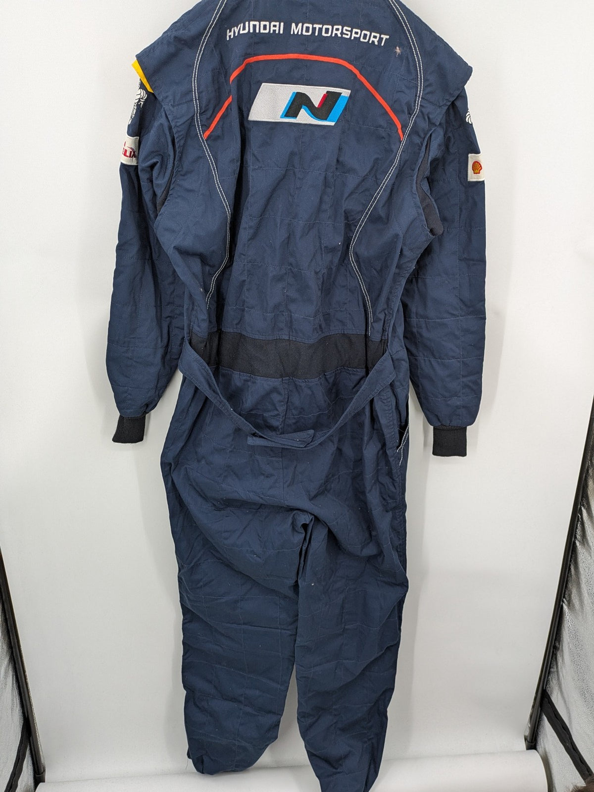 Hyundai Motorsport Sabelt racing suit navy blue with embroidered Shell and Michelin logos.