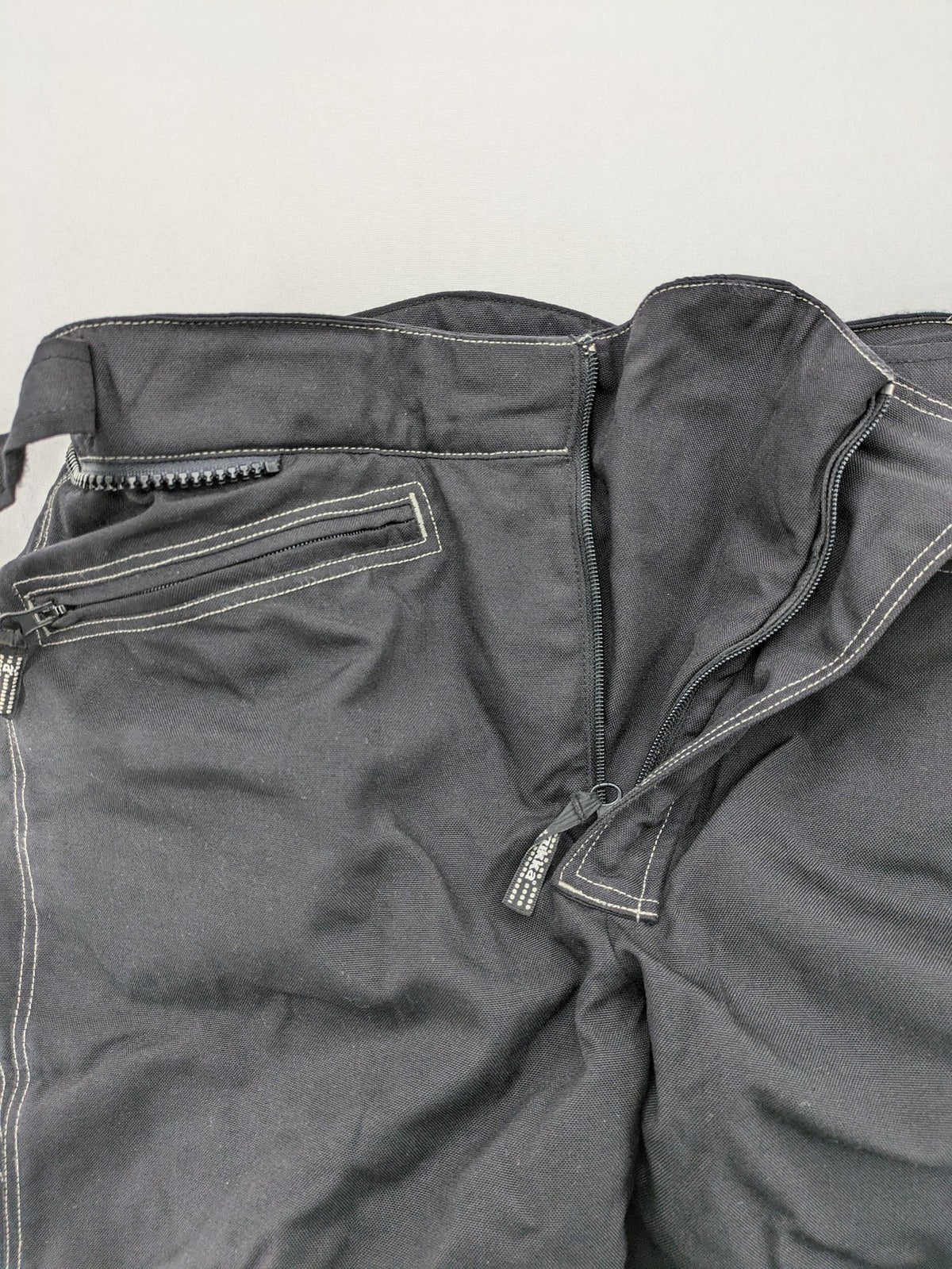 Rukka black motorcycle chaps with grey accents and CE knee protectors, made from durable Cordura.
