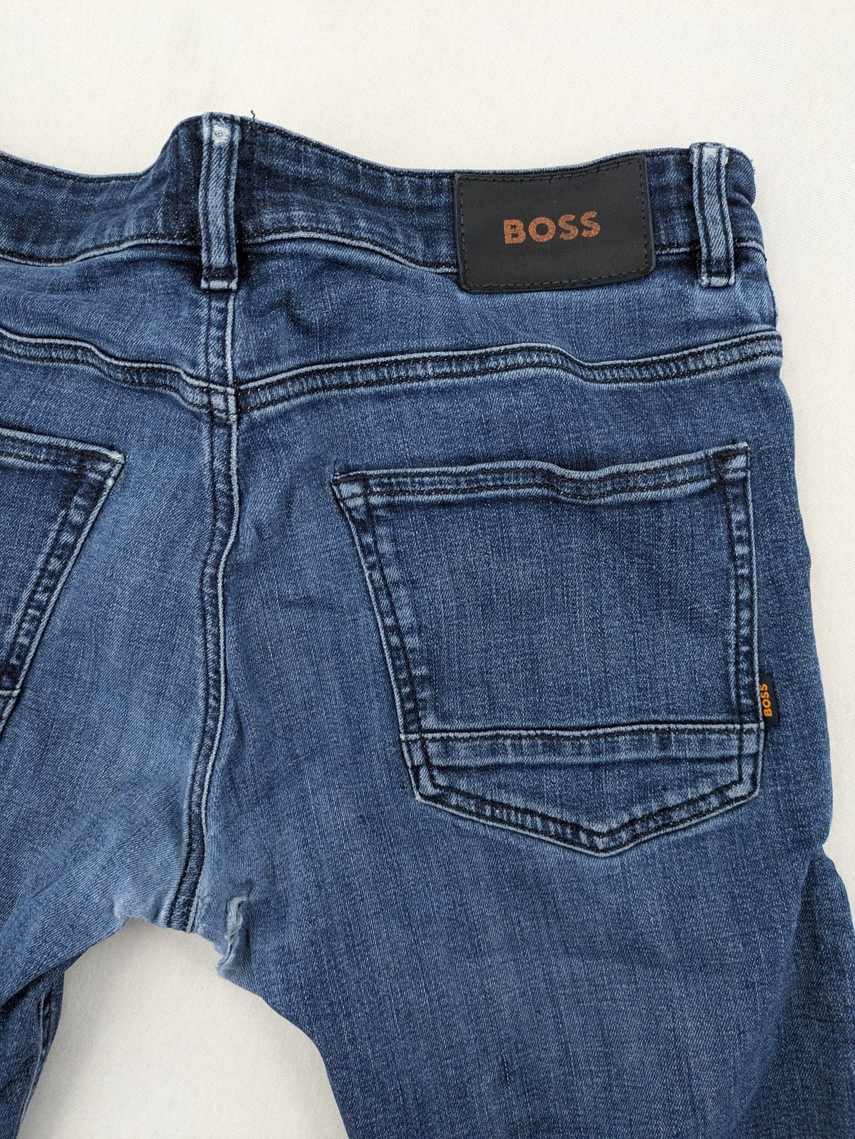 BOSS blue slim fit jeans with logo, five-pocket design, and button fly.