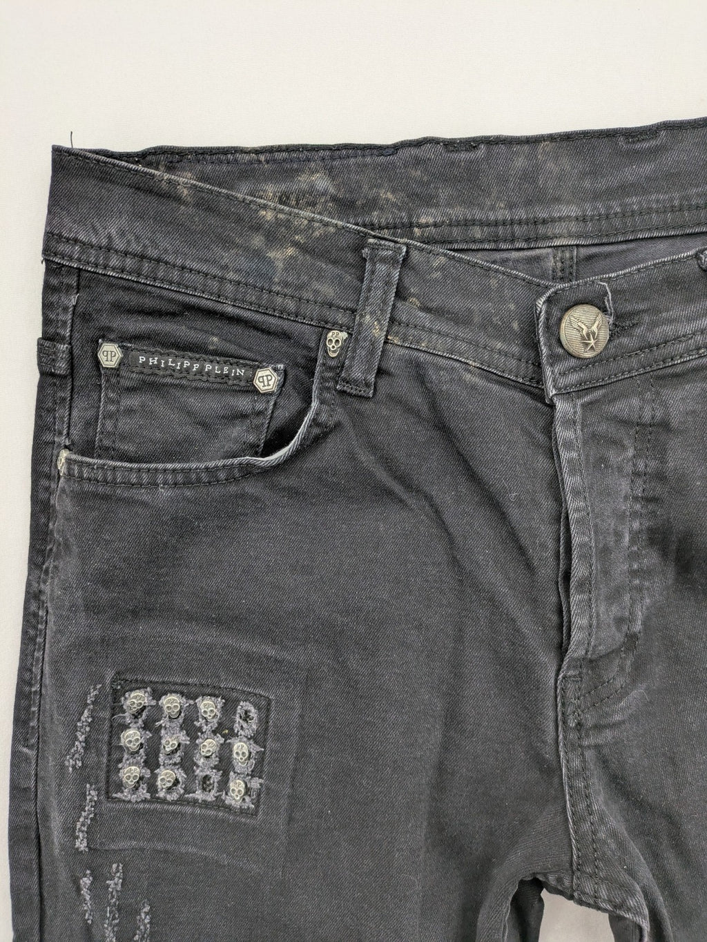 Philipp Plein black straight jeans with distressed finish and skull patch detail.
