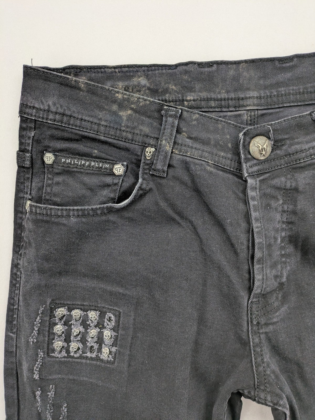 Philipp Plein black straight jeans with distressed finish and skull patch detail.