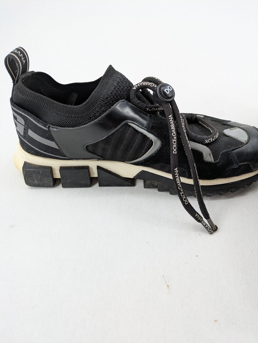 Dolce & Gabbana black sneakers with logo laces and segmented sole design.