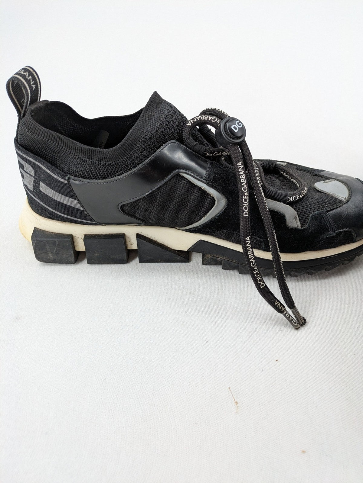 Dolce & Gabbana black sneakers with logo laces and segmented sole design.