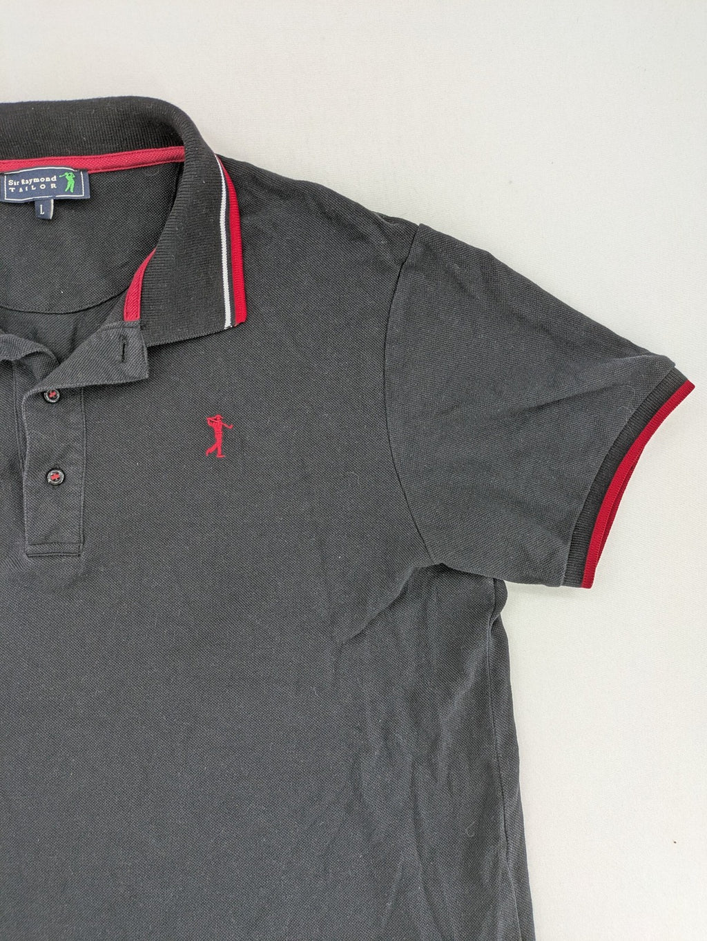 Sir Raymond Tailor black polo shirt with red and white striped collar, embroidered golfer logo.