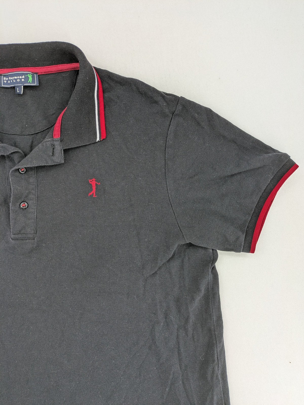 Sir Raymond Tailor black polo shirt with red and white striped collar, embroidered golfer logo.