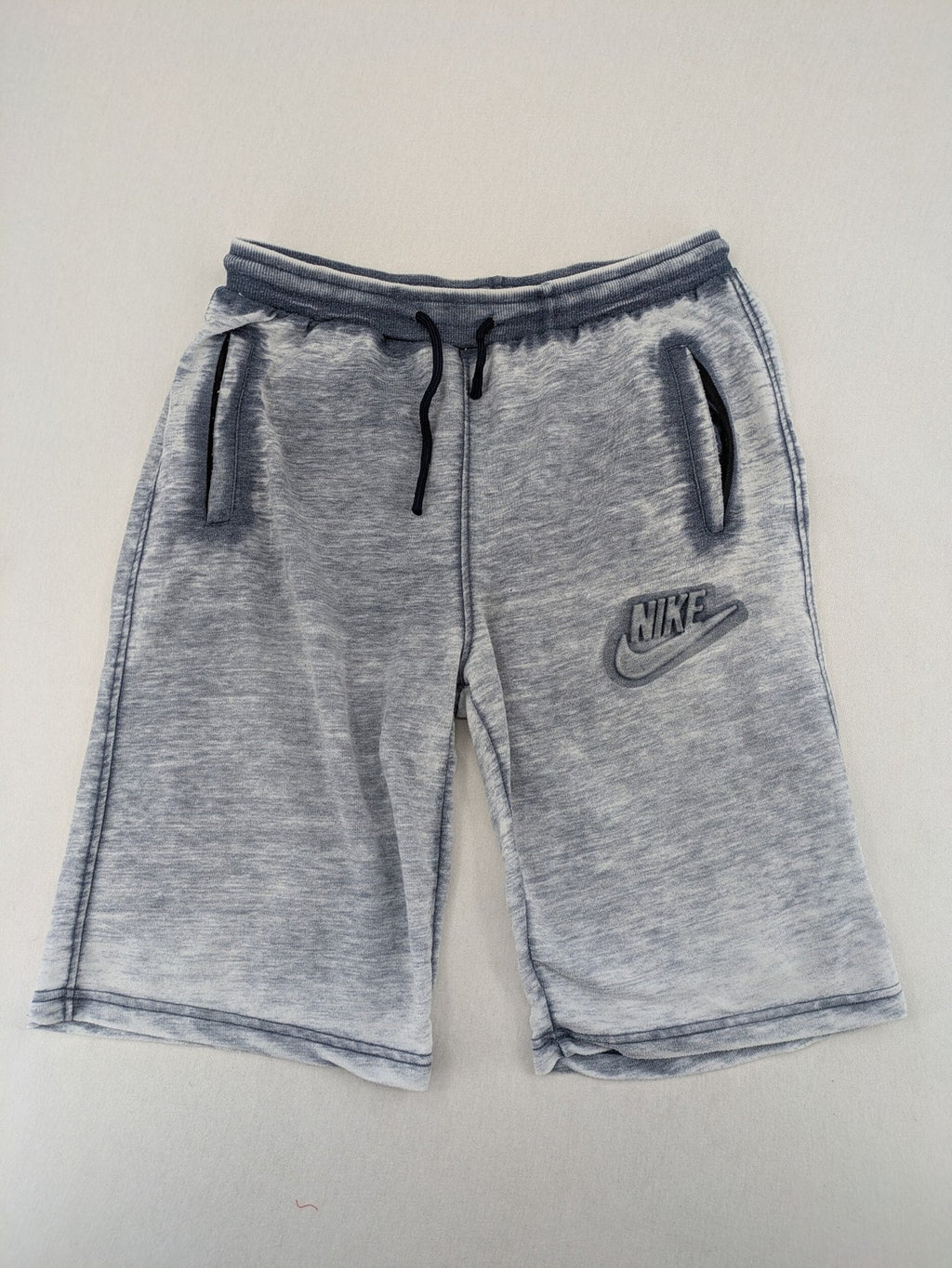 Nike grey acid wash jogger shorts with embossed logo and zip pockets.