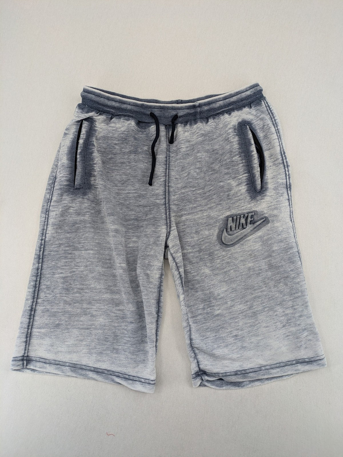 Nike grey acid wash jogger shorts with embossed logo and zip pockets.