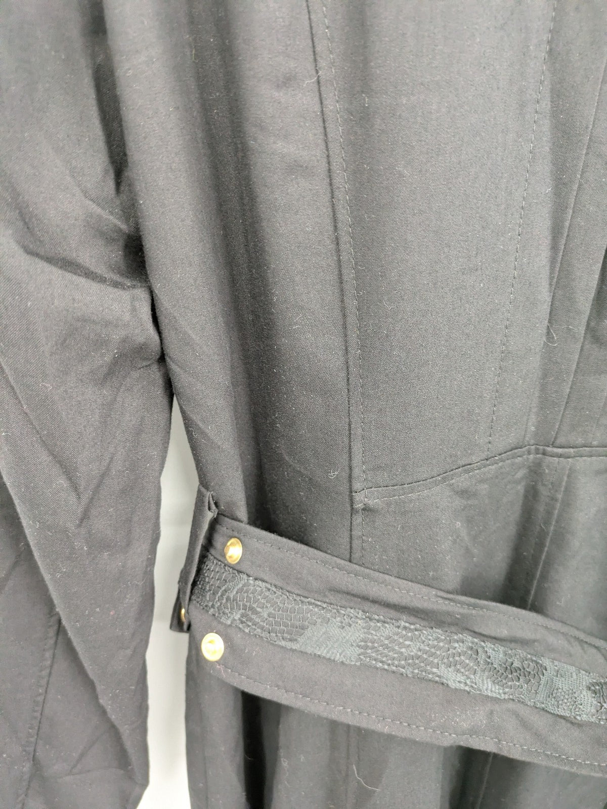Alvina black trench coat with lace collar and gold buttons, belted waist design.