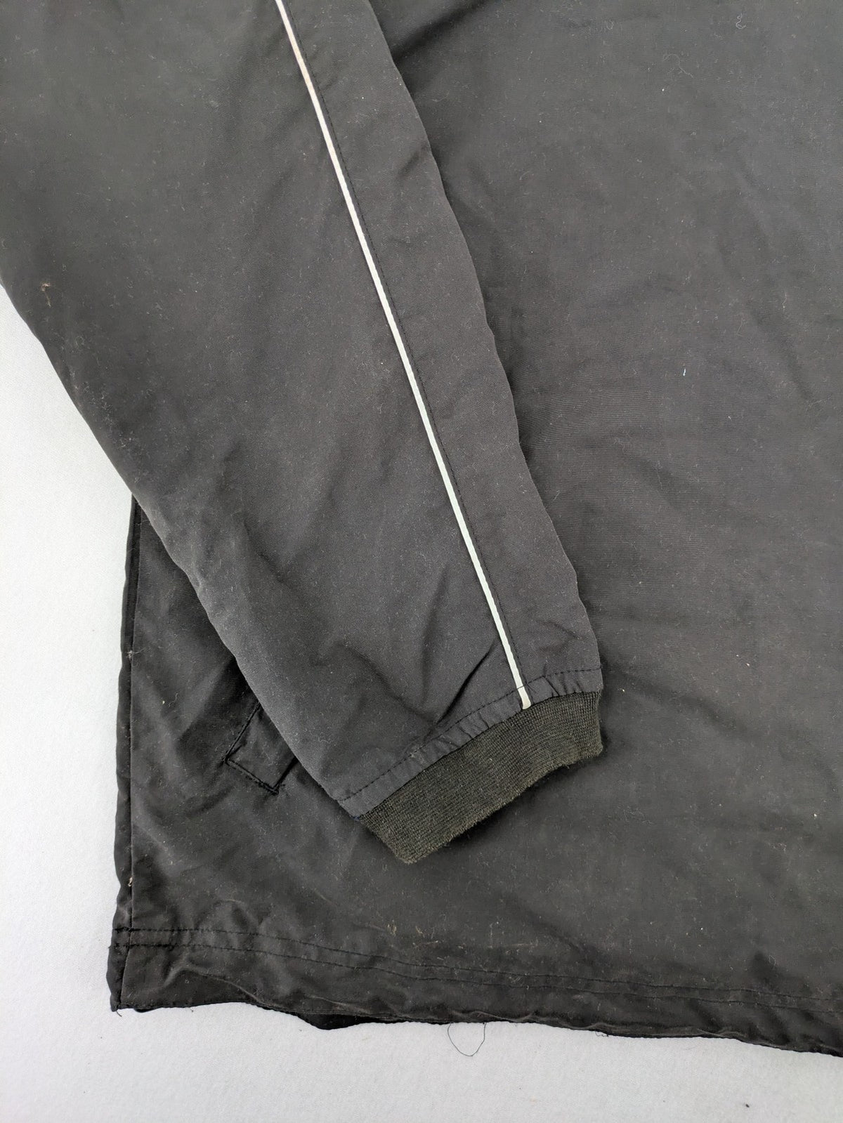 Tombo green windbreaker jacket with white piping, V-neck, and zippered pockets.