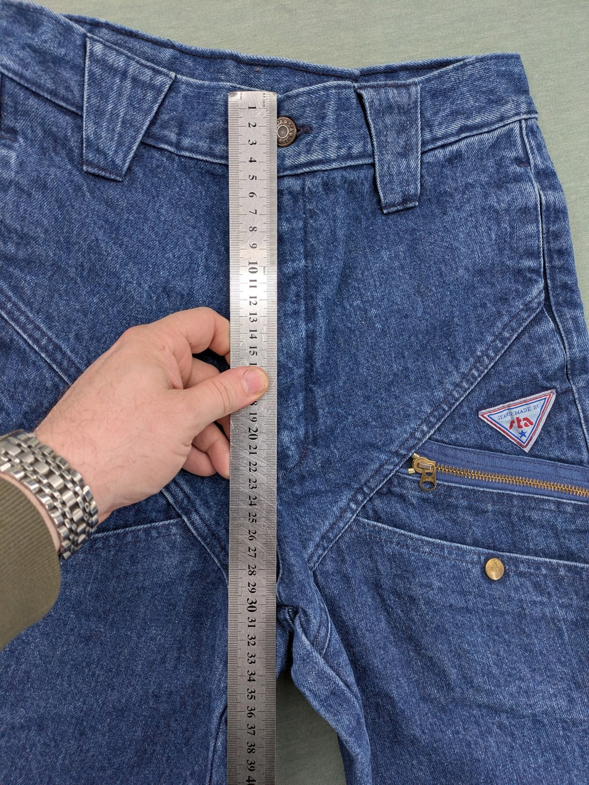 YKK blue high waist mom jeans with decorative front zipper pockets and vintage denim texture.
