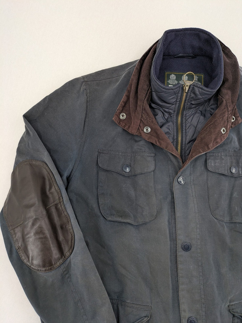 Barbour navy wax jacket with quilted lining and leather elbow patches, tartan interior.