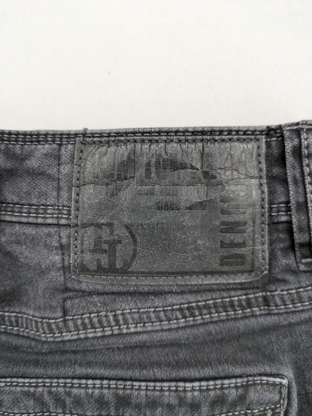 Tom Tompson grey slim tapered jeans with washed denim finish and subtle branding.