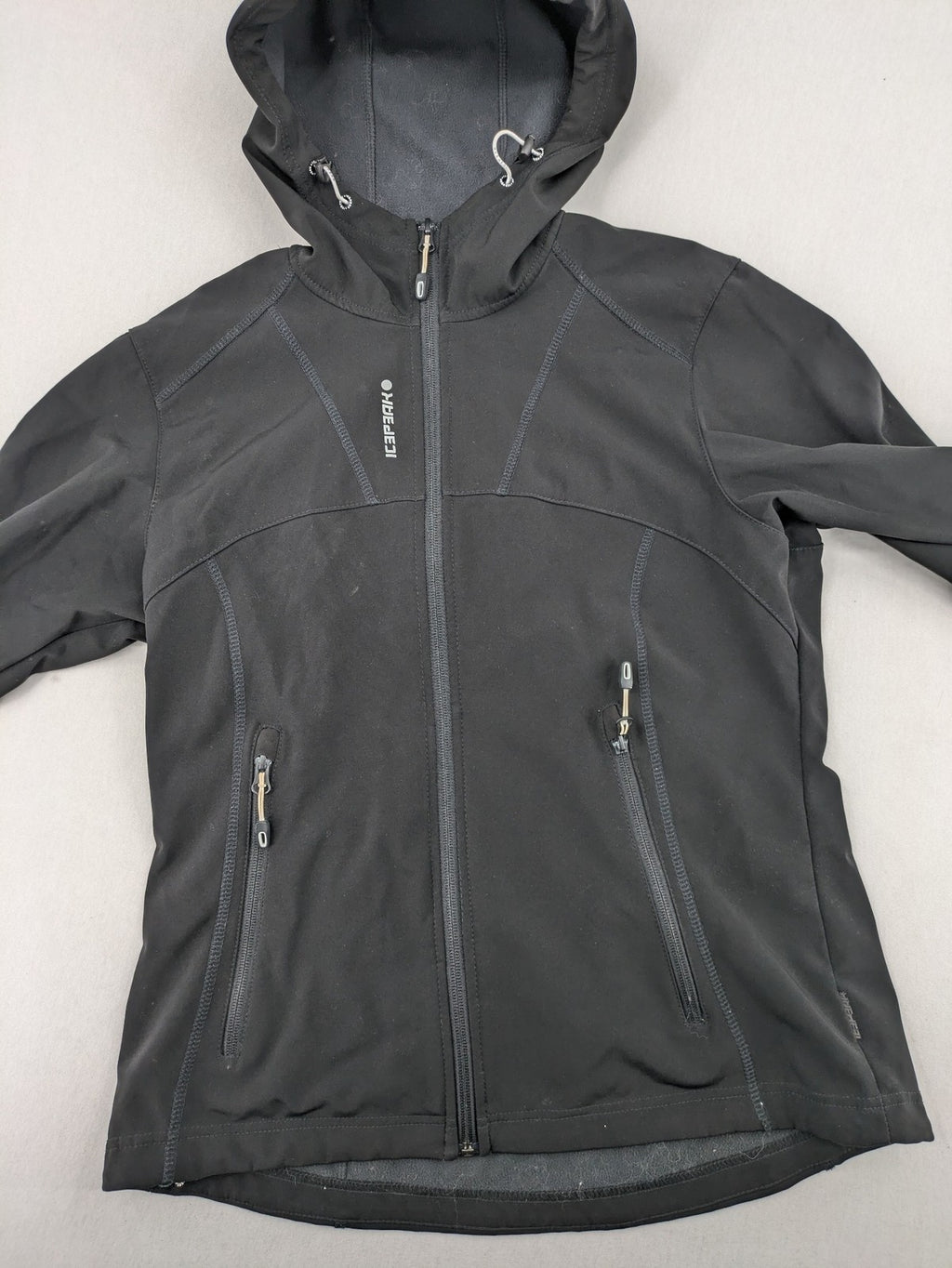 Icepeak black softshell jacket with fleece lining, adjustable hood, and zippered pockets.