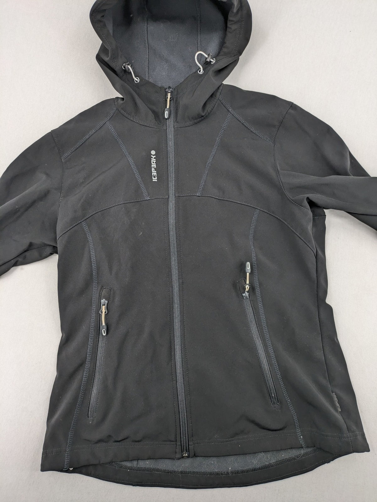 Icepeak black softshell jacket with fleece lining, adjustable hood, and zippered pockets.