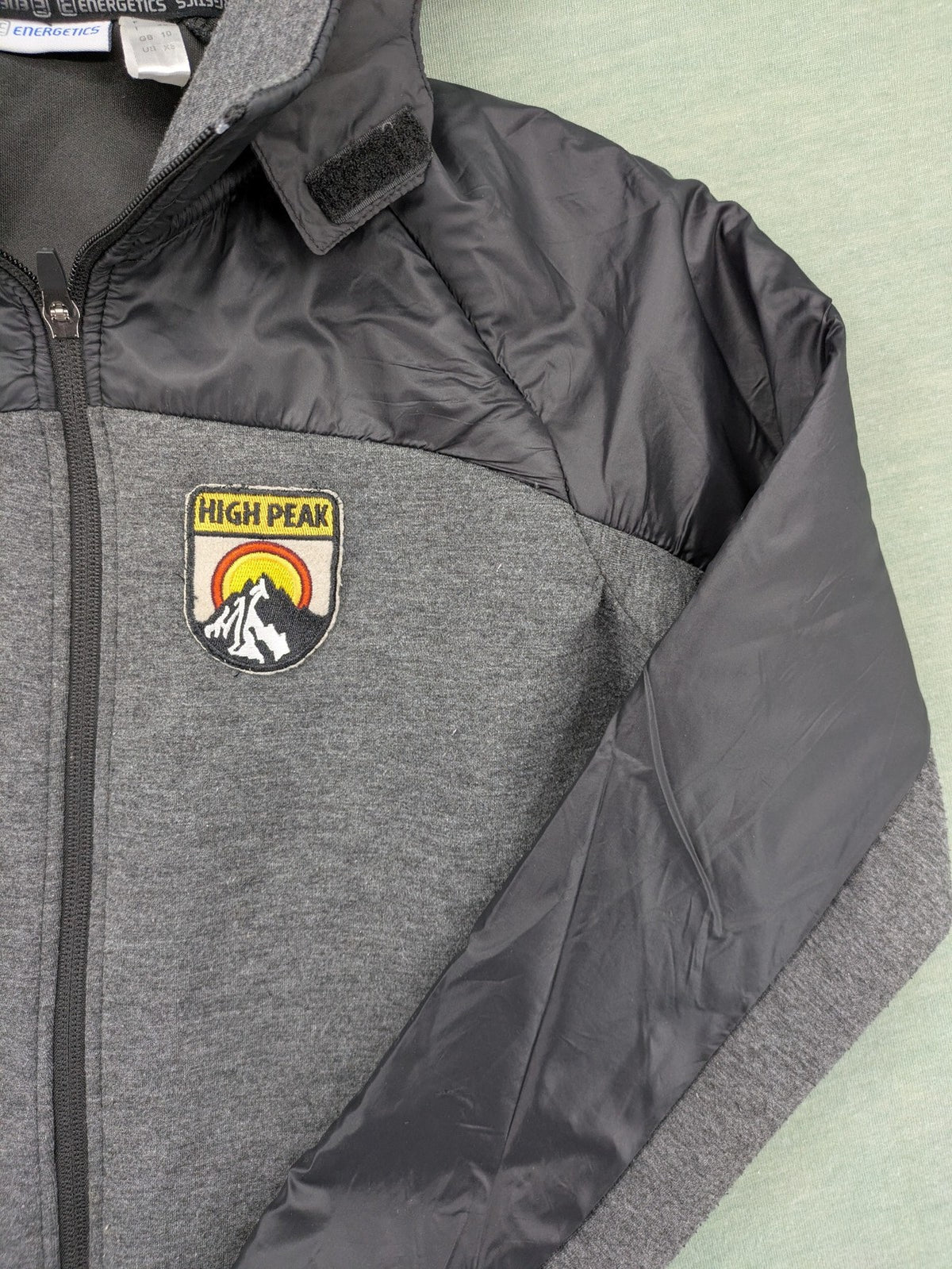 Energetics hybrid jacket black grey with High Peak patch and zip-up design.