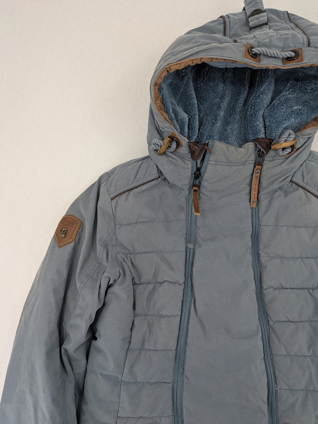 Naketano blue jacket with teddy fleece lining, hood, and leather appliqués.