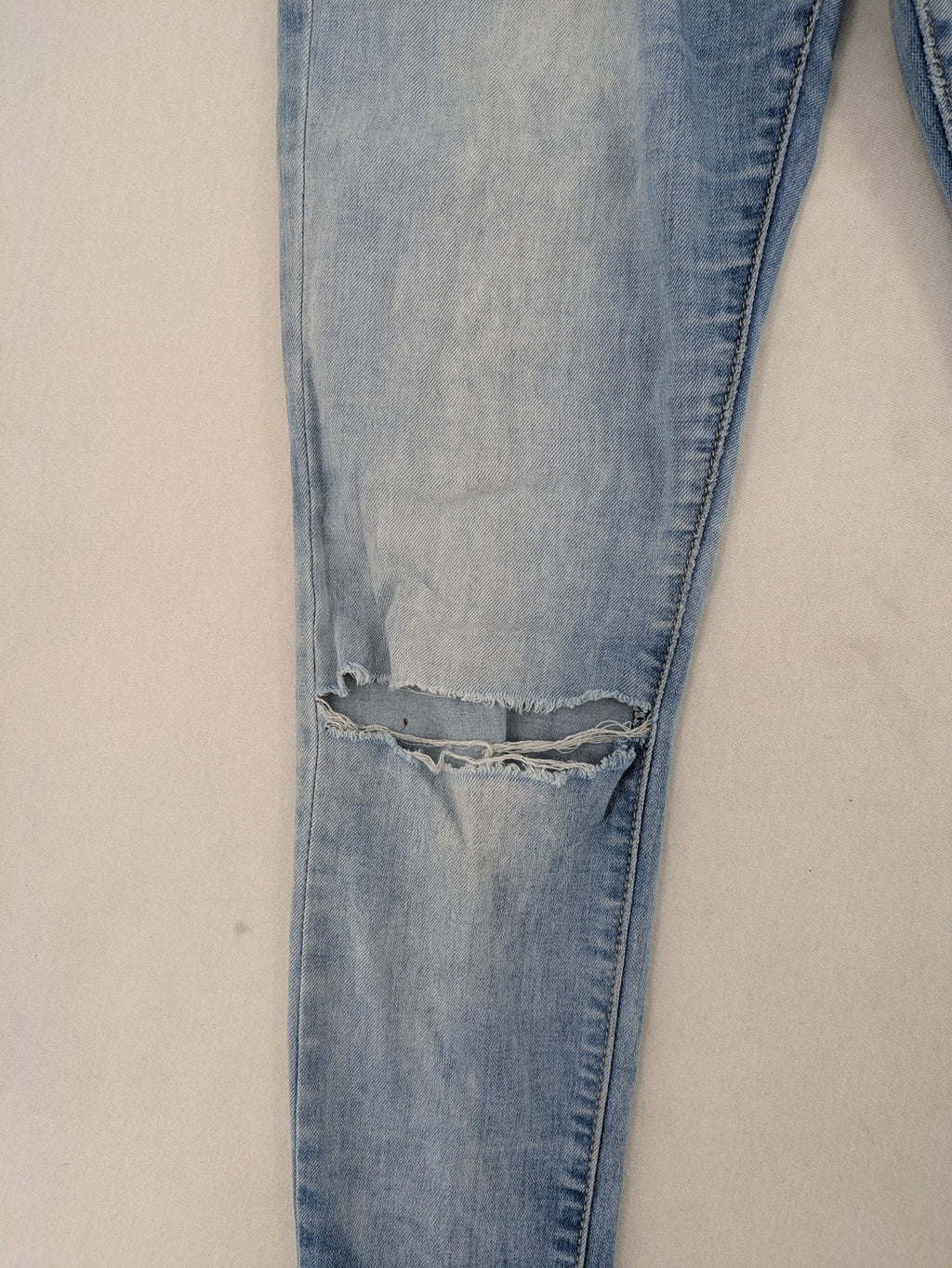 Lexxury blue skinny jeans distressed with knee rips and light wash finish.