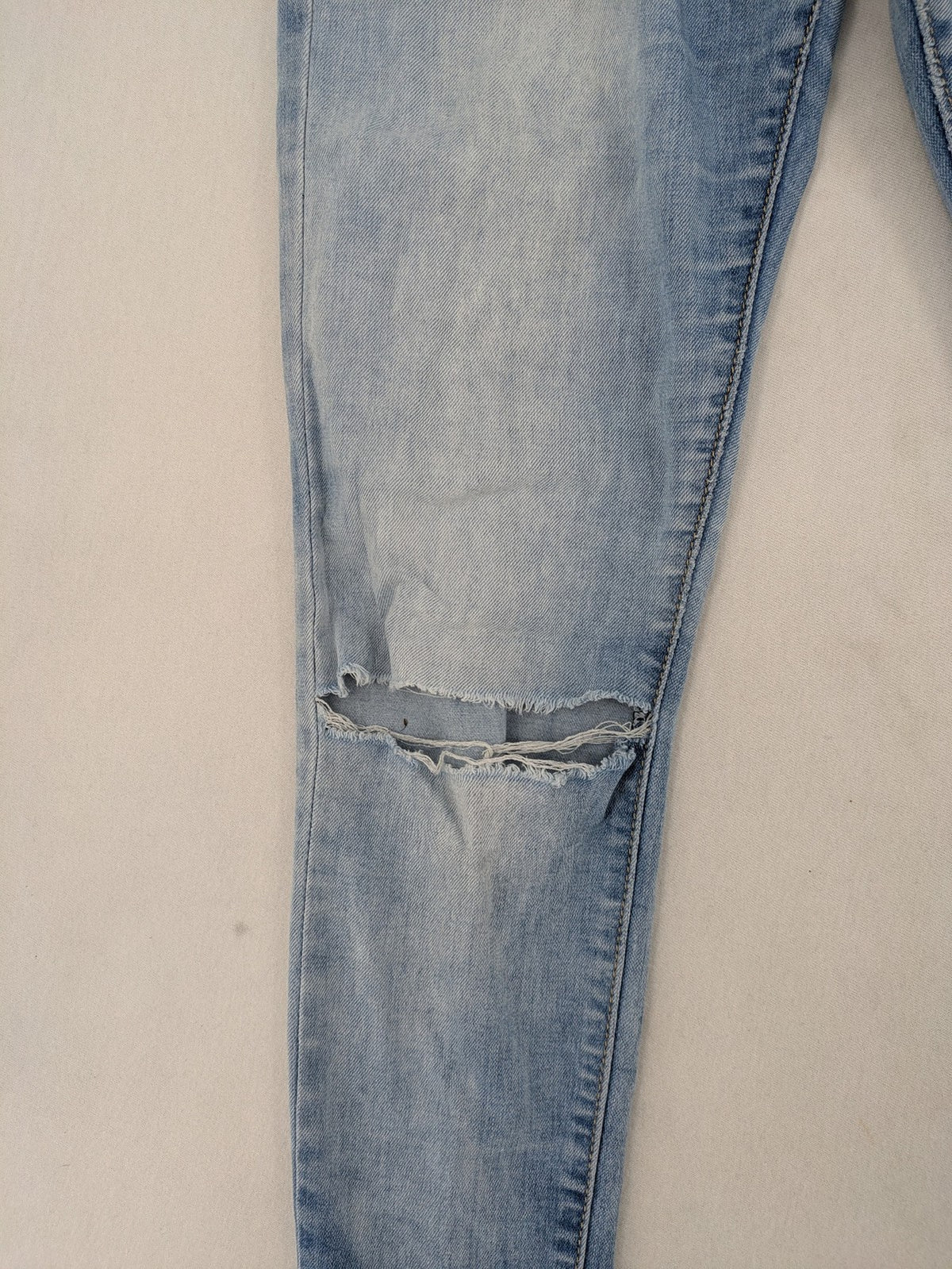 Lexxury blue skinny jeans distressed with knee rips and light wash finish.