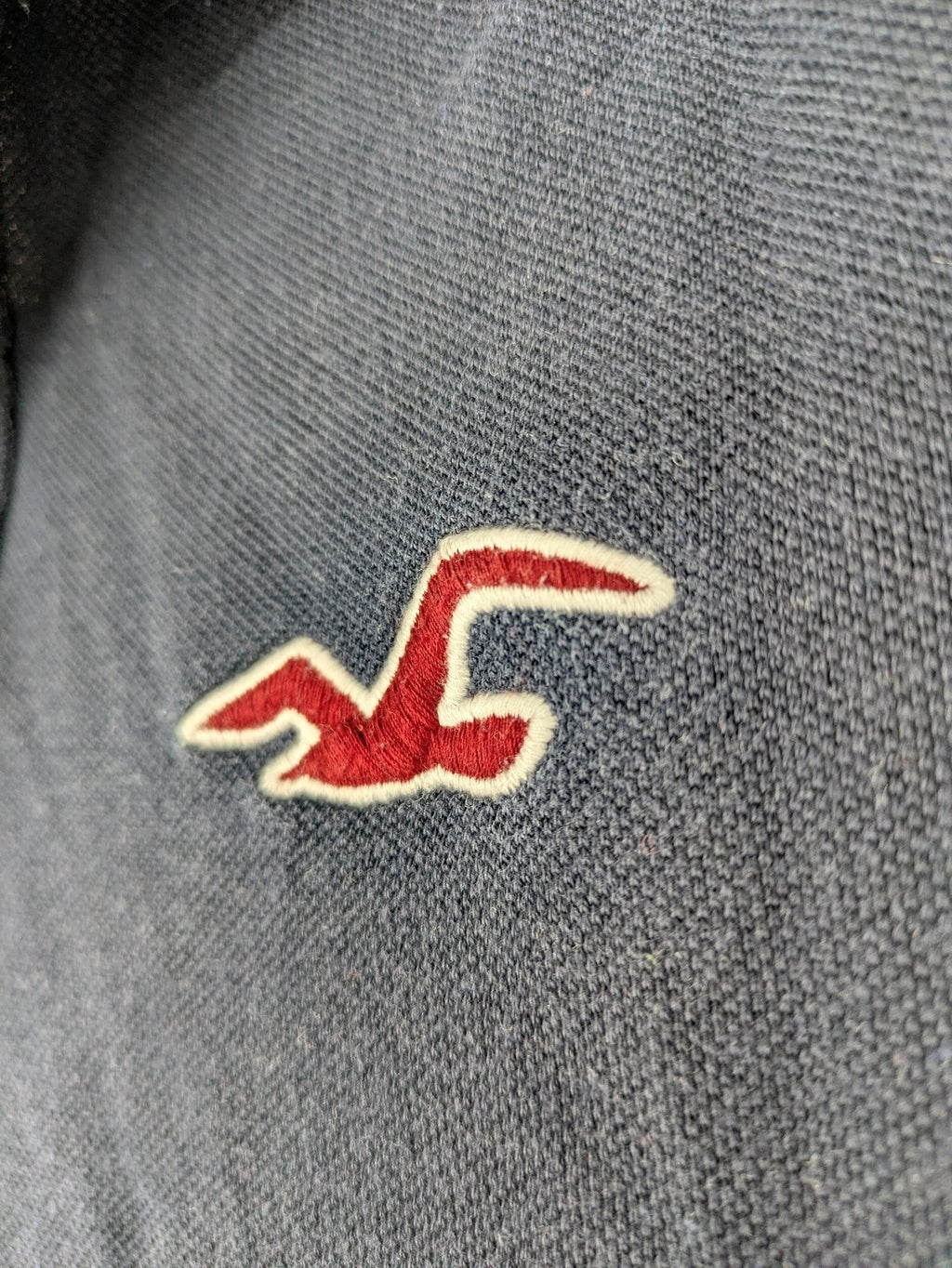 Hollister navy polo shirt with embroidered seagull logo and classic collar.