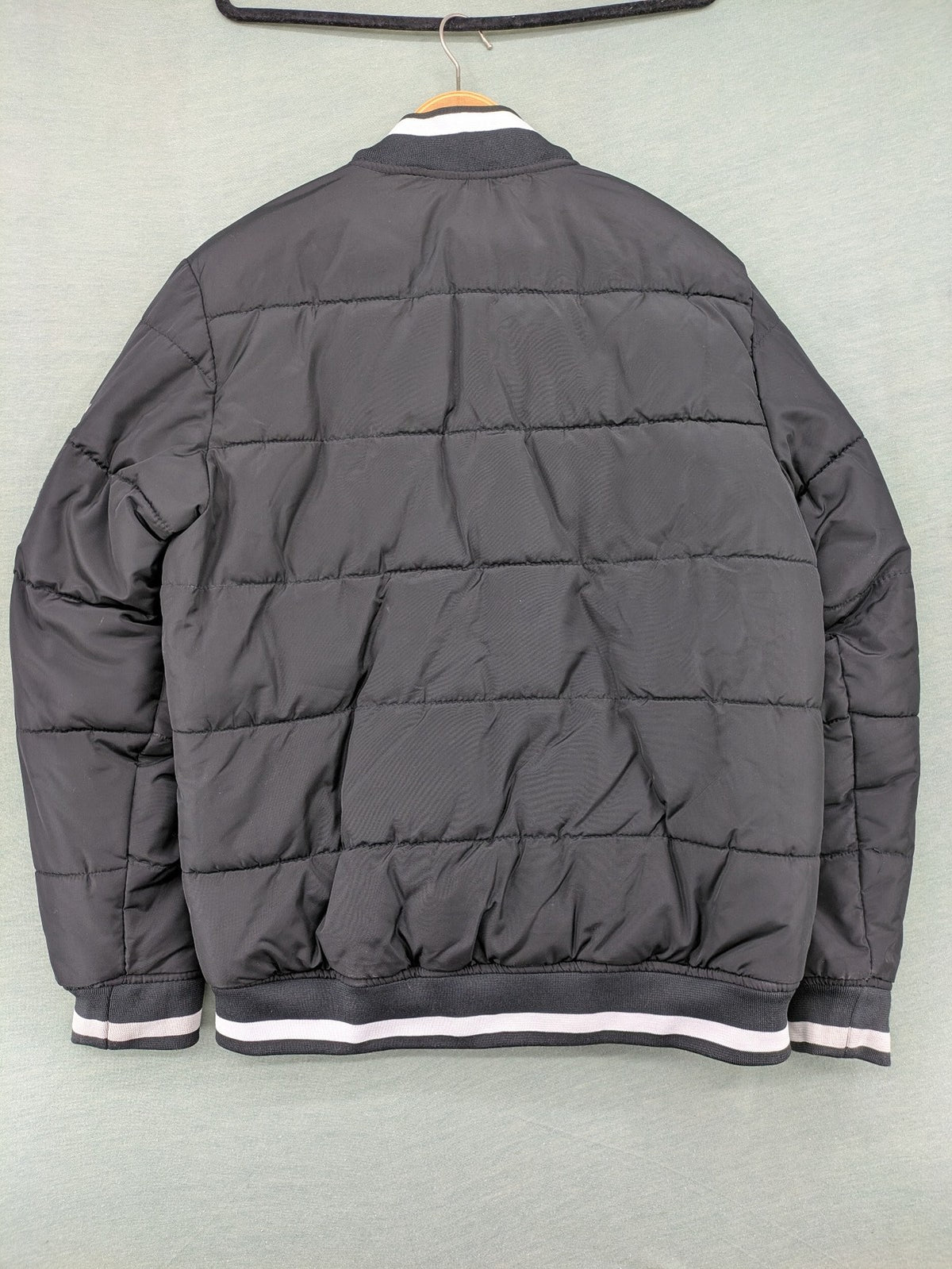 Chapter black bomber jacket with patches, striped ribbed cuffs, and full zip closure.