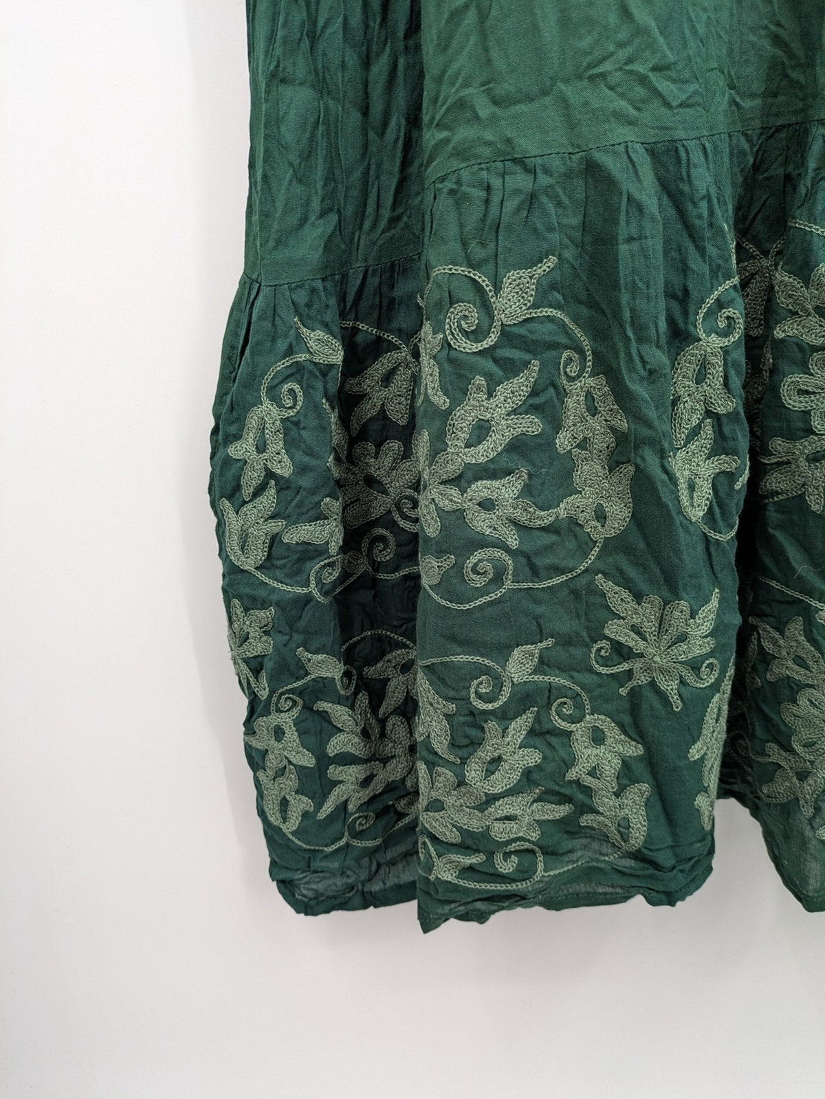 Boho green maxi dress with floral embroidery along tiered hem and adjustable spaghetti straps.