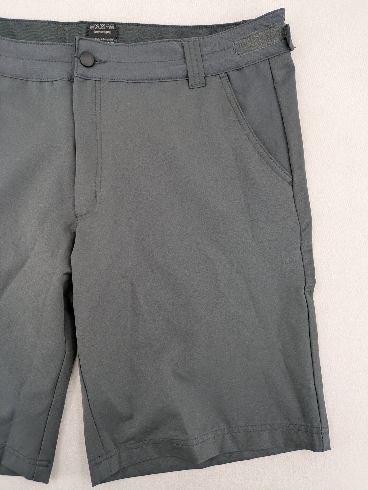 Outdoor grey functional shorts with adjustable velcro waistband and zippered leg pocket.