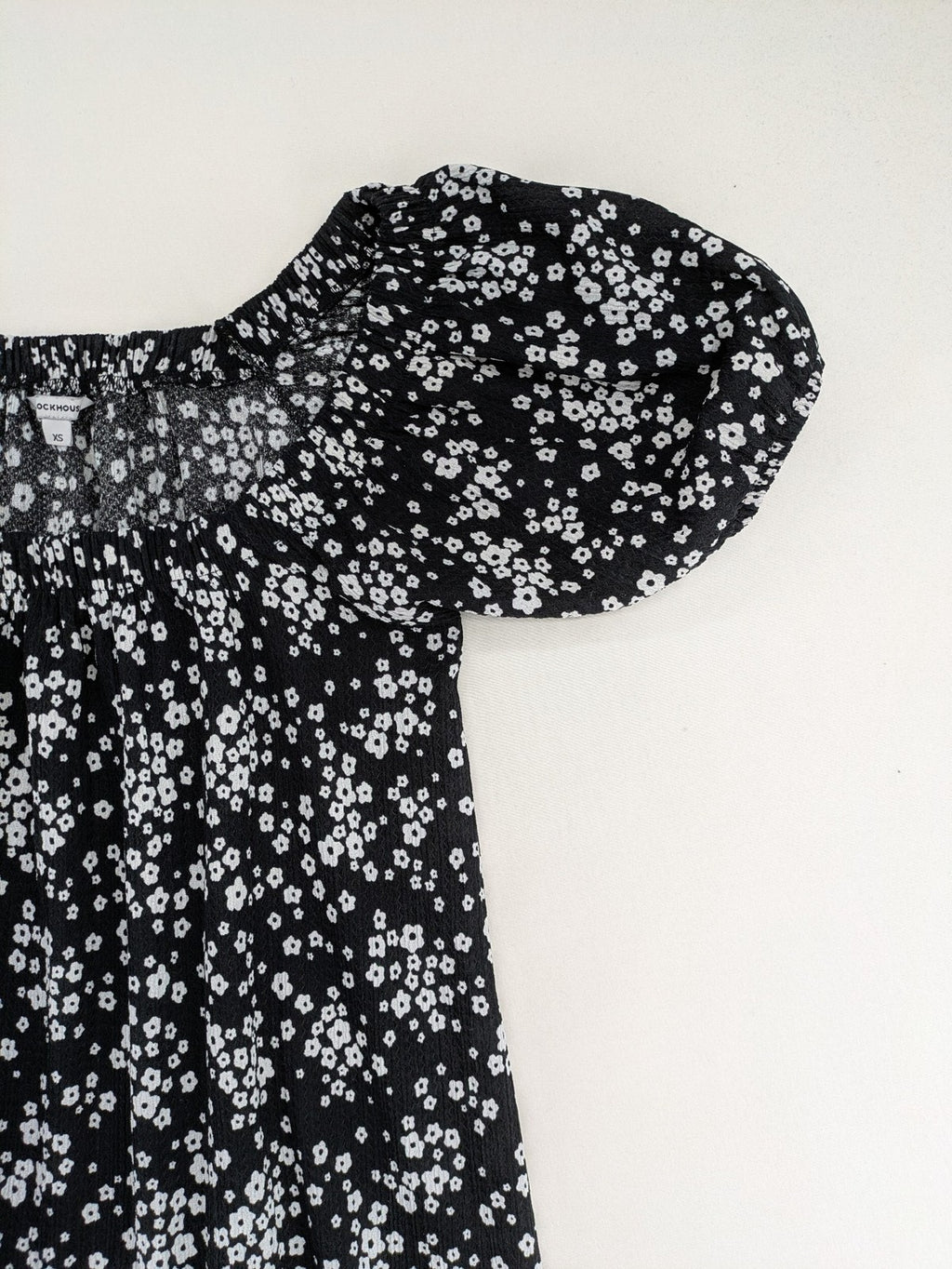 Clockhouse black and white floral mini dress with smocked bodice and puff sleeves.