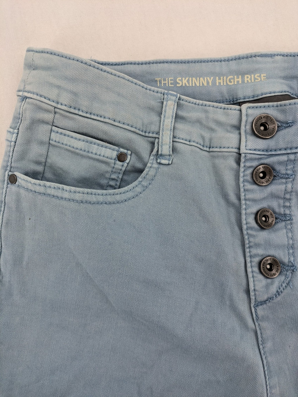 Yessica blue skinny jeans high rise with button fly and V-cut hem detail.