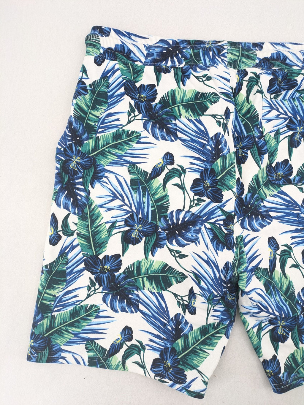 Nils Sundström blue and green tropical floral shorts with white background and elastic waistband.
