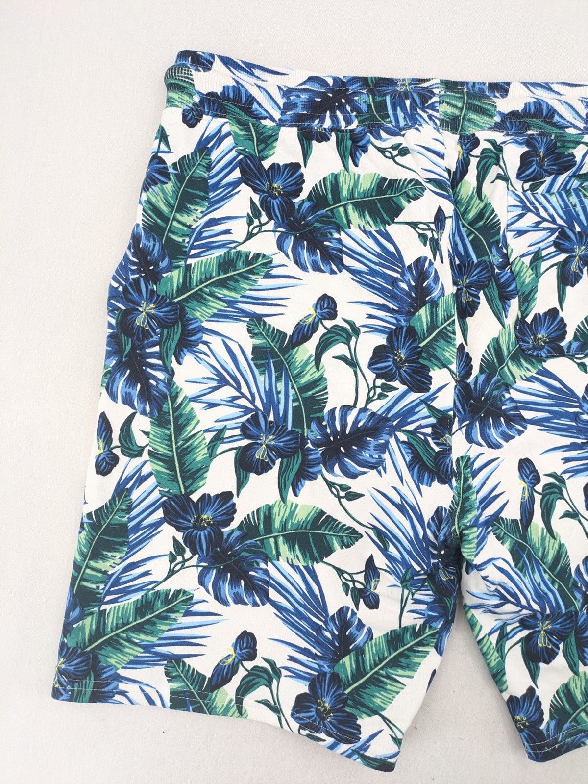 Nils Sundström blue and green tropical floral shorts with white background and elastic waistband.