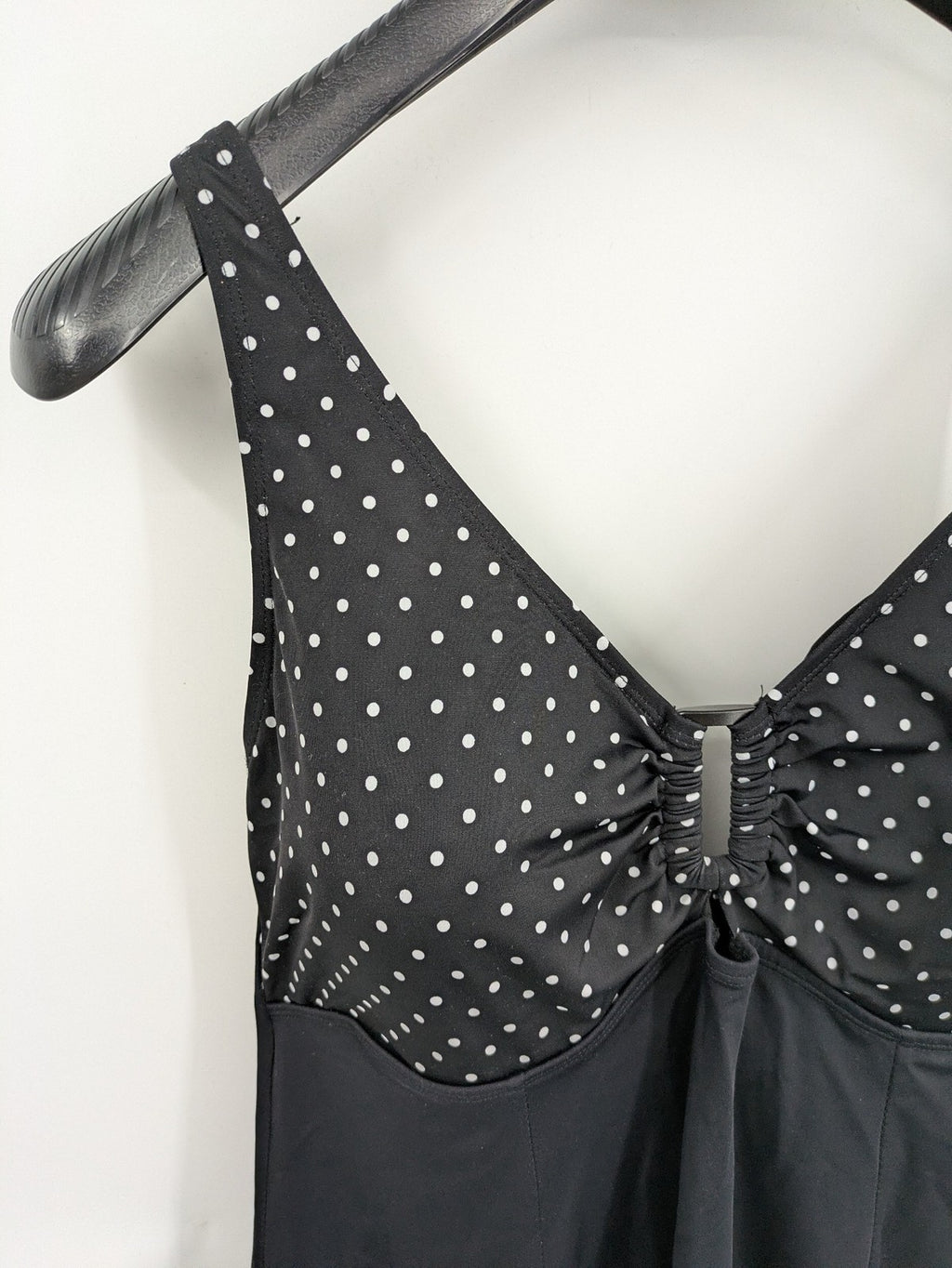 Elegante black swimsuit with white polka dots, V-neck, adjustable straps, and padded cups.