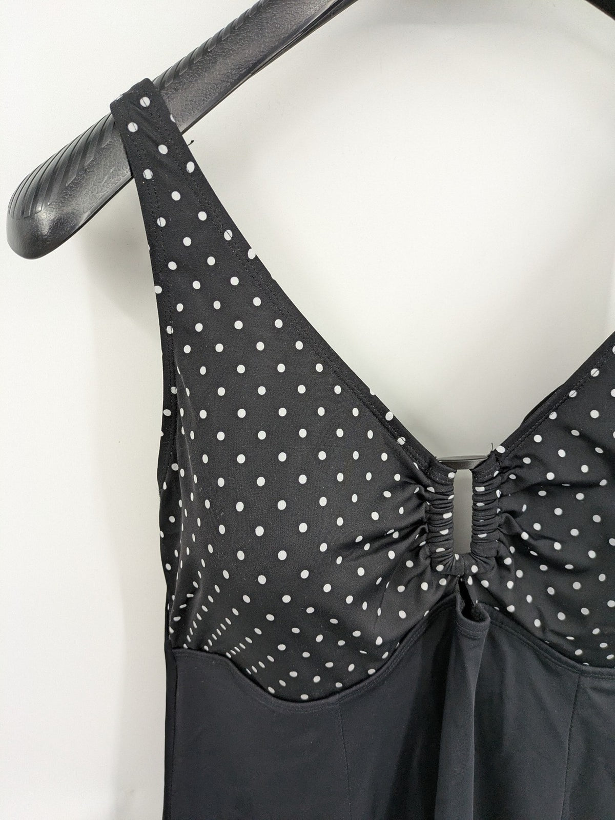Elegante black swimsuit with white polka dots, V-neck, adjustable straps, and padded cups.