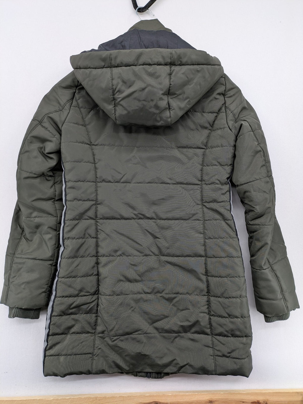 Vero Moda green puffer coat with quilted design and hood, featuring zipper and button closure.