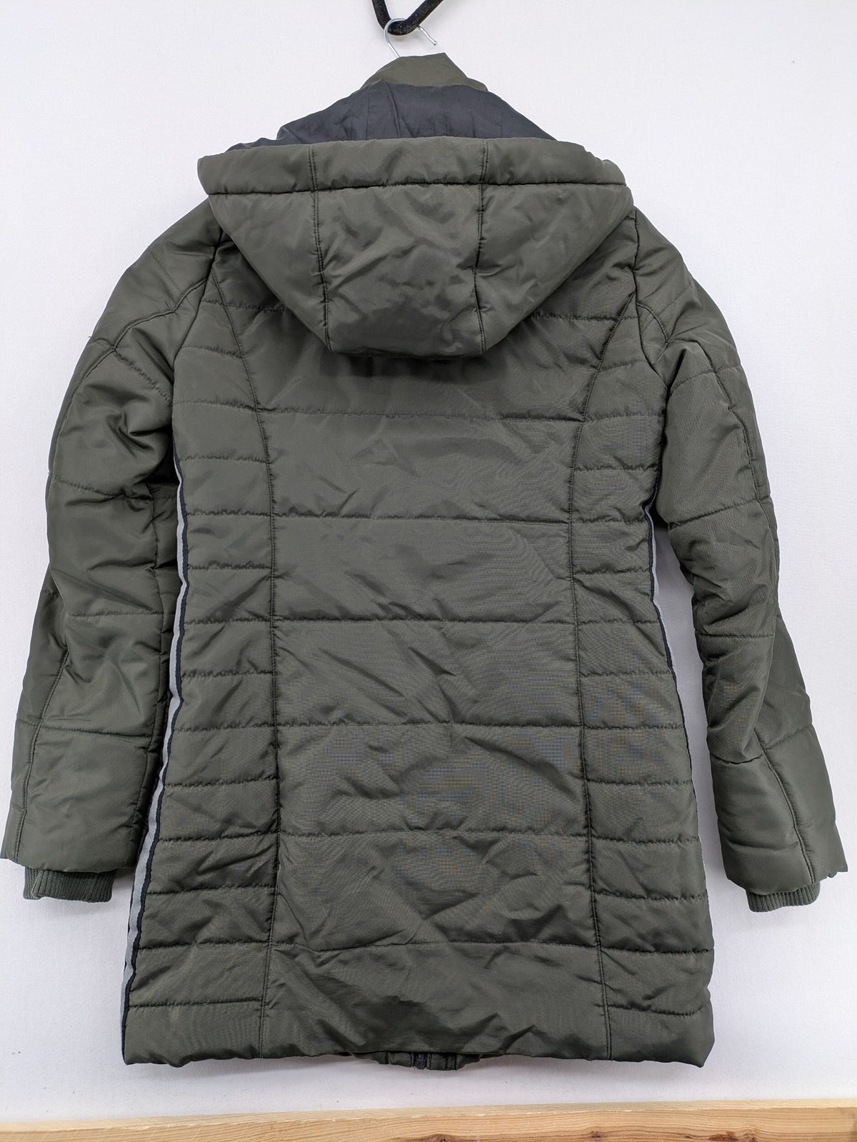 Vero Moda green puffer coat with quilted design and hood, featuring zipper and button closure.