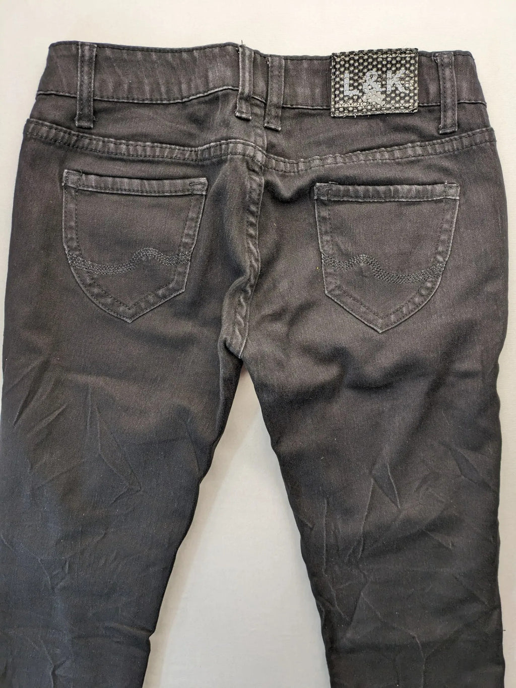 L & K Kaha black straight jeans with rhinestone logo patch and classic 5-pocket design.