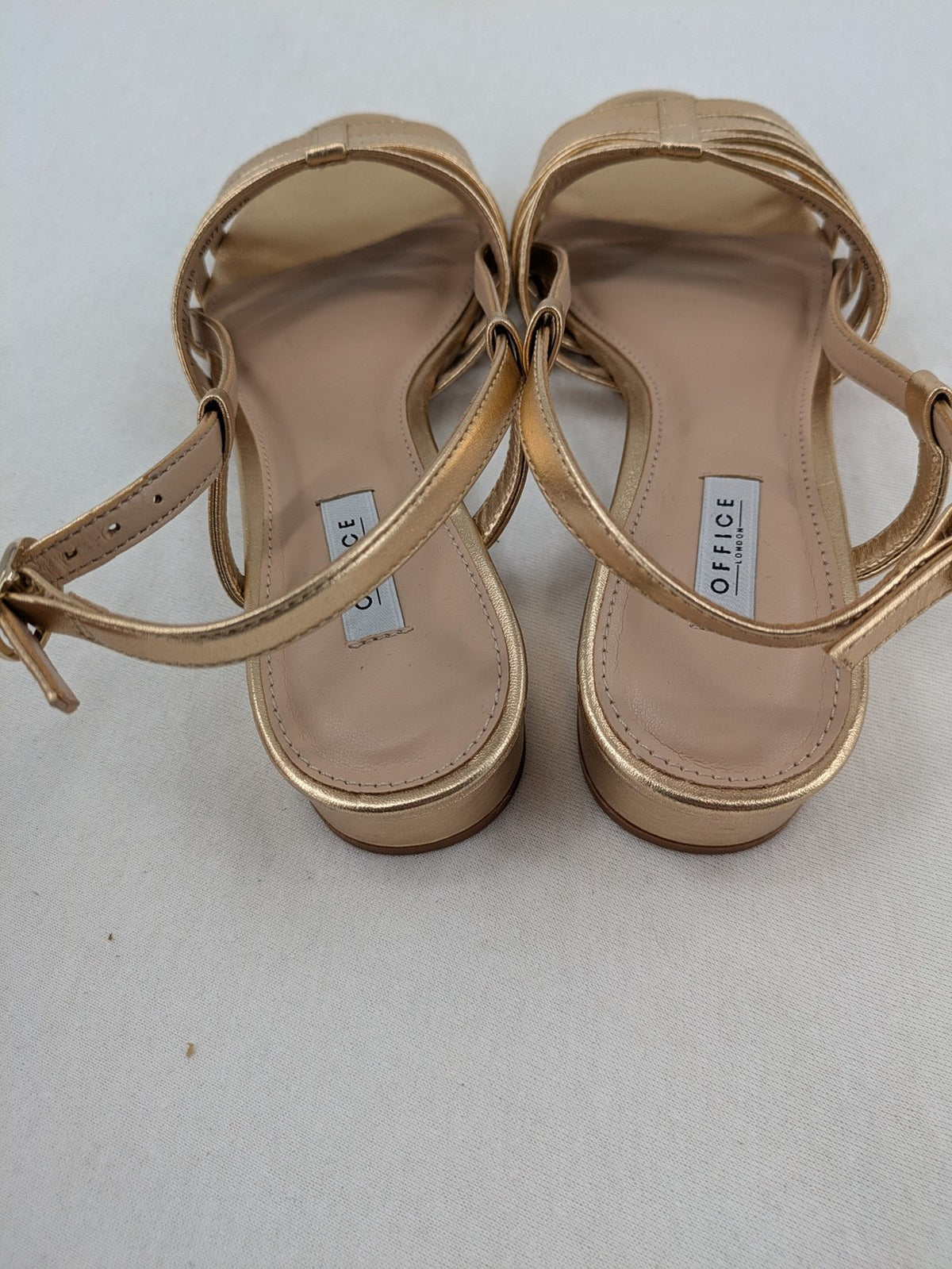 Office London gold metallic sandals with adjustable ankle strap and block heel design.