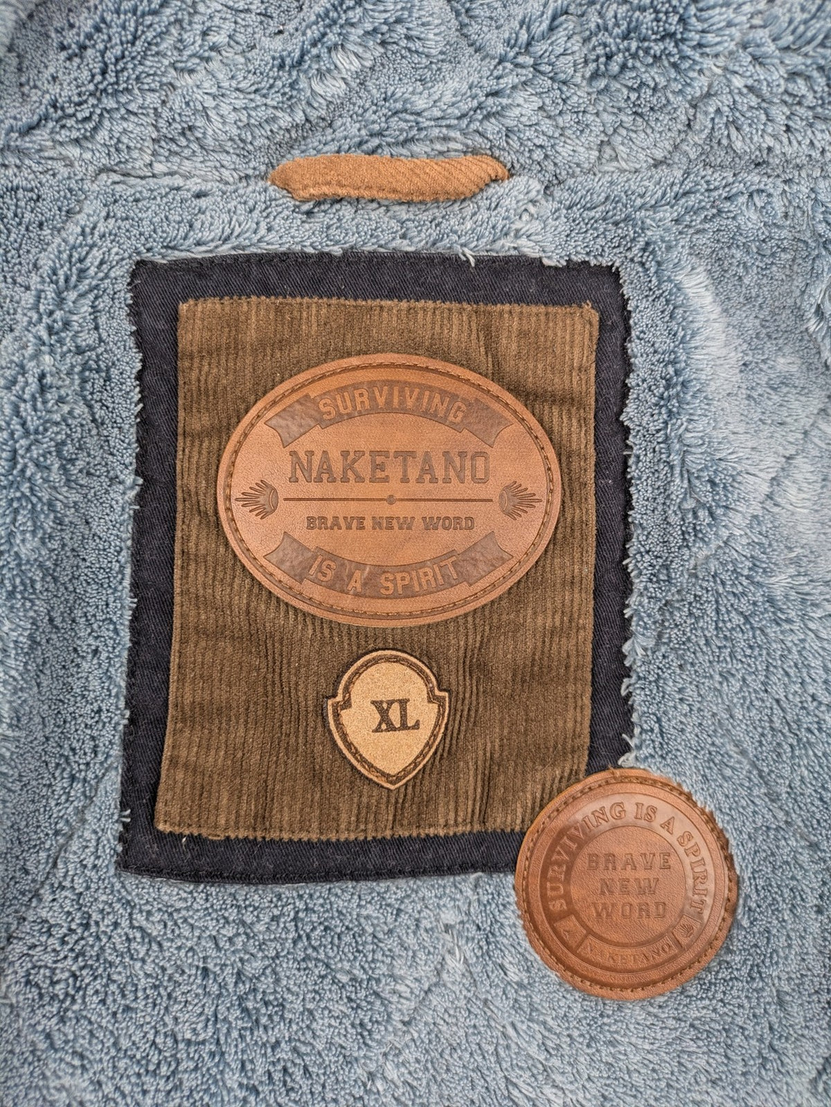 Naketano blue jacket with teddy fleece lining, hood, and leather appliqués.
