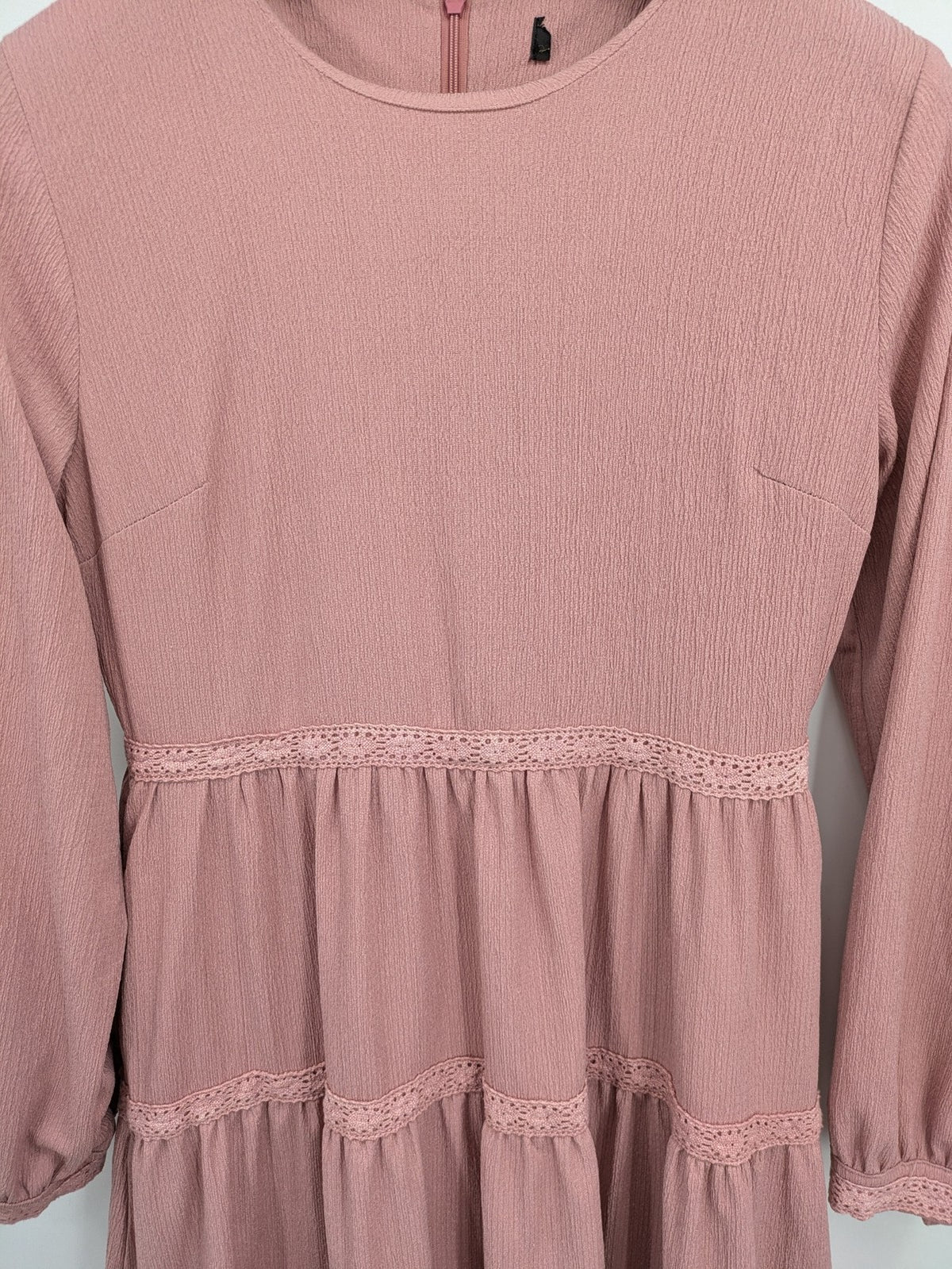 Moda pink bridal party dress with lace inserts, long sleeves, and tiered design.