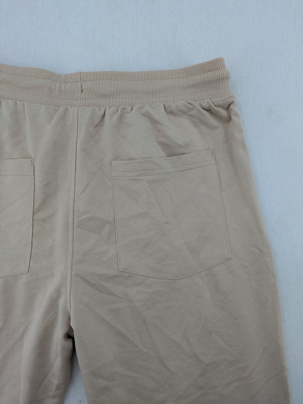 Naruto Shippuden beige joggers featuring Naruto Uzumaki graphic and logo print.