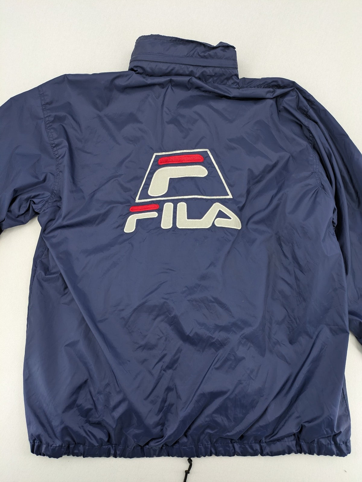 Fila navy windbreaker jacket with large embroidered logo on chest and back.