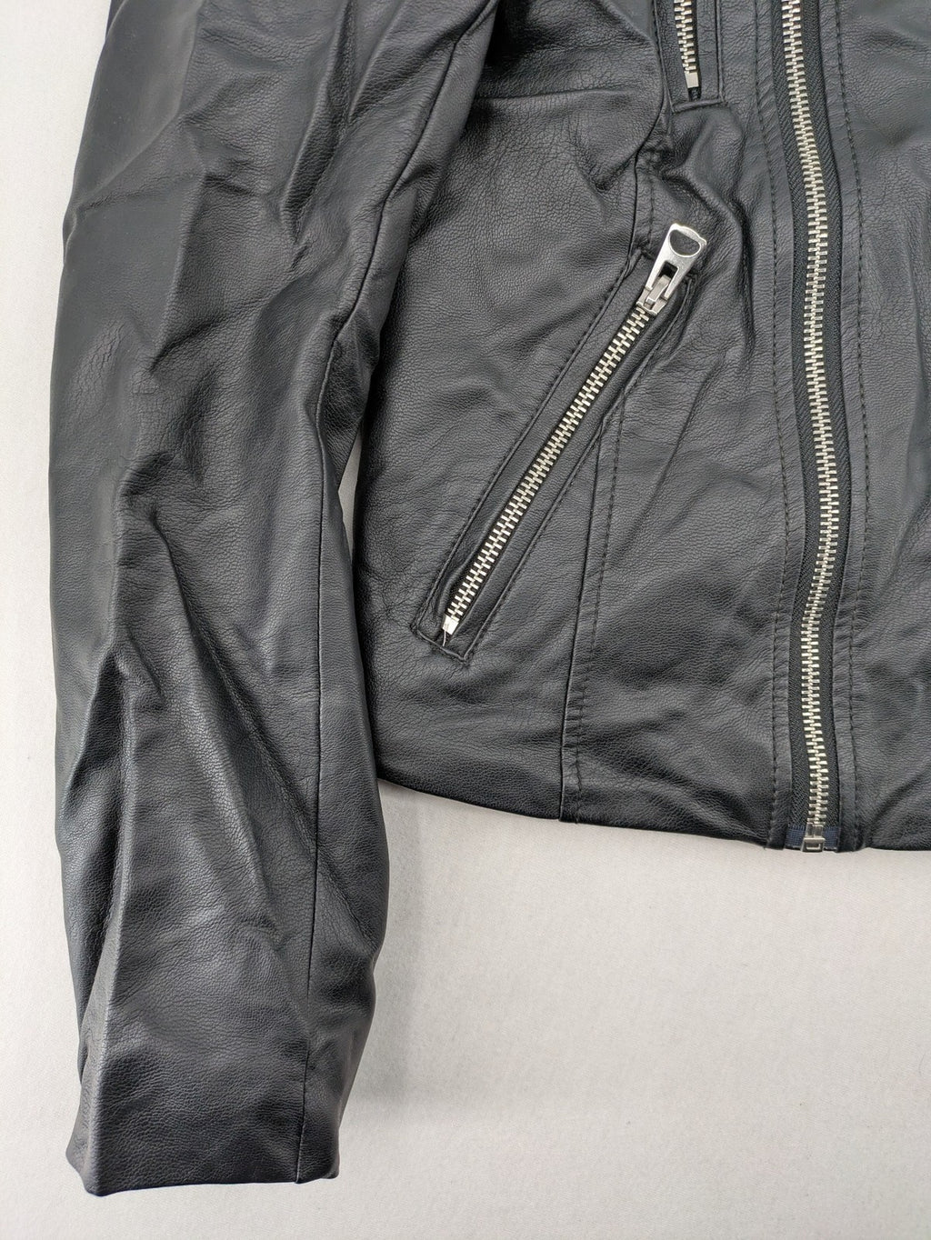H&M black biker jacket with silver zippers, shoulder flaps, and snap-button details.