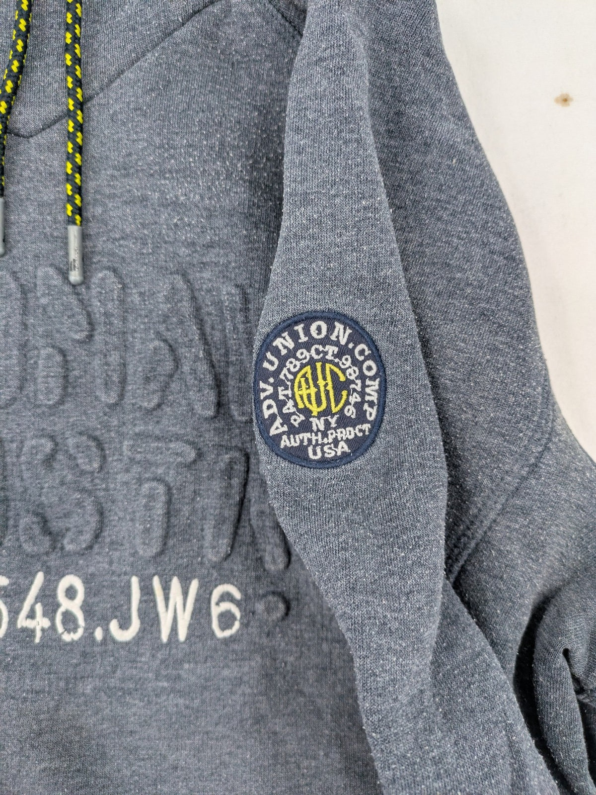 C&A grey hoodie with embossed chest logo, teddy-lined hood, and side zip pockets.