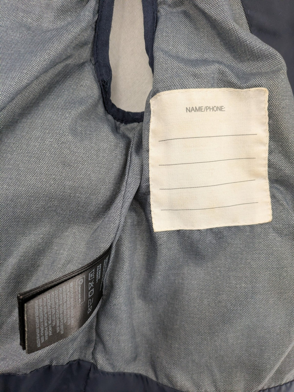 H&M navy puffer vest with grey hood and zip pockets for kids.
