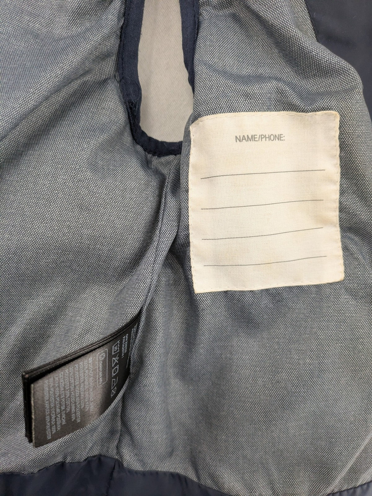 H&M navy puffer vest with grey hood and zip pockets for kids.