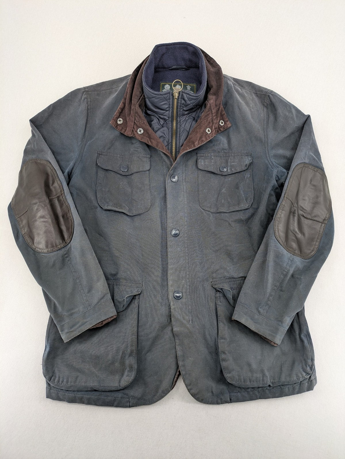 Barbour navy wax jacket with quilted lining and leather elbow patches, tartan interior.