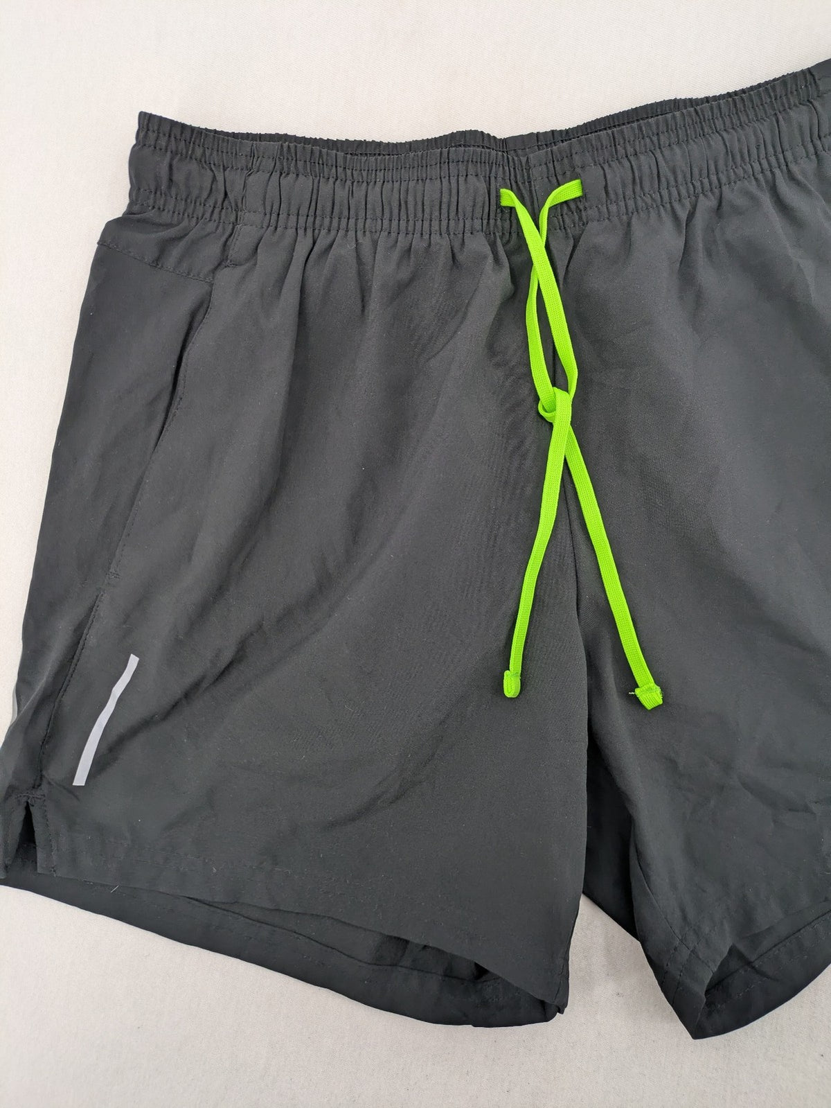 Crivit black running shorts with neon green accents, elastic waistband, and reflective details.