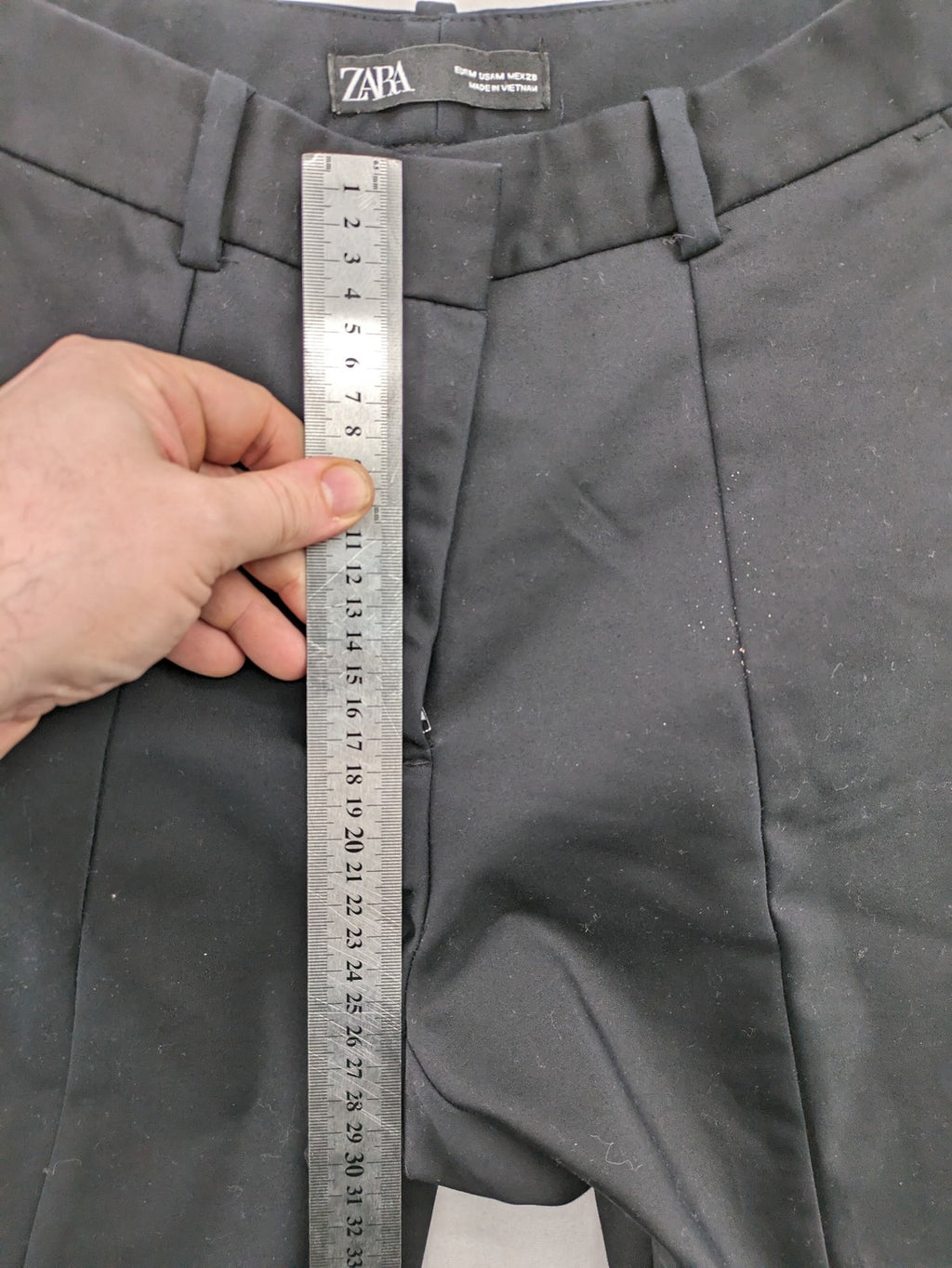 Zara black pants with front creases, subtle slit hem, and buttoned back pocket.